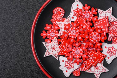 Seramik tabaklar, zencefilli çörekler ve koyu beton arkaplanda yeni yıl süslemelerinin diğer unsurlarından oluşan güzel bir Noel kompozisyonu