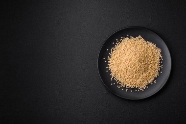 Koyu beton arka planda seramik bir kasede çiğ ptitim makarna. İsrail gıda hazırlığı