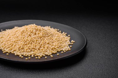 Koyu beton arka planda seramik bir kasede çiğ ptitim makarna. İsrail gıda hazırlığı