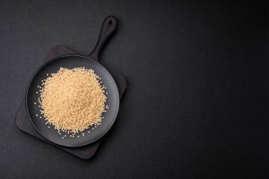 Koyu beton arka planda seramik bir kasede çiğ ptitim makarna. İsrail gıda hazırlığı