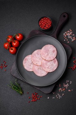 Lezzetli taze jambon, tuz, baharat ve otlarla kesilmiş koyu beton arka planda yuvarlak dilimler halinde.