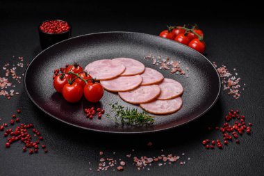 Lezzetli taze jambon, tuz, baharat ve otlarla kesilmiş koyu beton arka planda yuvarlak dilimler halinde.