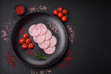 Lezzetli taze jambon, tuz, baharat ve otlarla kesilmiş koyu beton arka planda yuvarlak dilimler halinde.