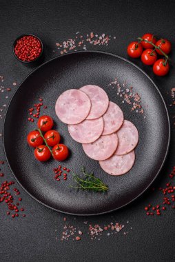 Lezzetli taze jambon, tuz, baharat ve otlarla kesilmiş koyu beton arka planda yuvarlak dilimler halinde.