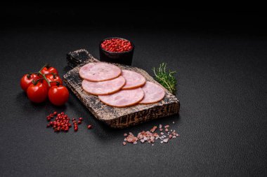 Lezzetli taze jambon, tuz, baharat ve otlarla kesilmiş koyu beton arka planda yuvarlak dilimler halinde.