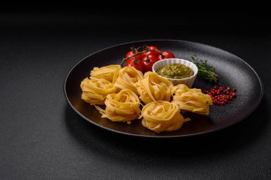 Tuz, baharat ve otlu, koyu beton arka planda pesto soslu lezzetli taze makarna.