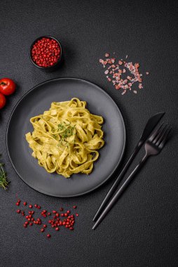 Pesto soslu lezzetli taze makarna, tuz, baharatlar ve çimento kaplı seramik bir tabakta otlar.