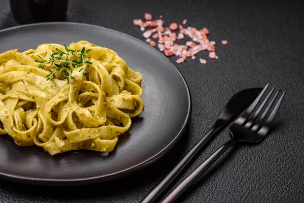 Pesto soslu lezzetli taze makarna, tuz, baharatlar ve çimento kaplı seramik bir tabakta otlar.