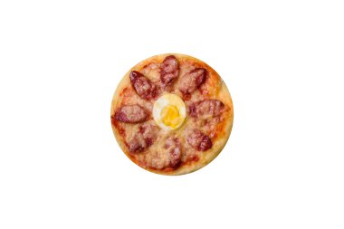 Homemade pizza with sausages, tomatoes, cheese, spices and herbs on a wooden cutting board against a dark concrete background