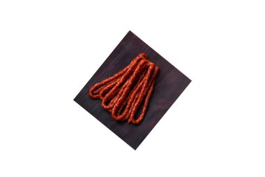 Lezzetli ince tütsülenmiş et sosisleri, baharatlar ve otlar koyu beton arka planda.