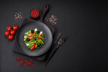 Lezzetli taze fasulye, bezelye, tatlı biber ve peynir salatası. Koyu beton bir arka planda tuz ve baharatlarla.