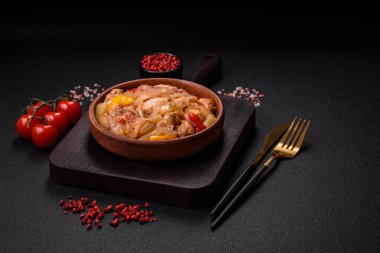 Lezzetli bir yemek tavuk dilimleri, tatlı biber ve soğan ile tuzlu ve baharatlı koyu beton arka planda.