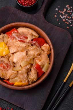 Lezzetli bir yemek tavuk dilimleri, tatlı biber ve soğan ile tuzlu ve baharatlı koyu beton arka planda.