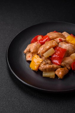 Lezzetli bir yemek tavuk dilimleri, tatlı biber ve soğan ile tuzlu ve baharatlı koyu beton arka planda.