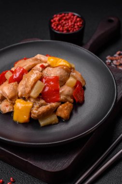 Lezzetli bir yemek tavuk dilimleri, tatlı biber ve soğan ile tuzlu ve baharatlı koyu beton arka planda.