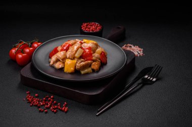 Lezzetli bir yemek tavuk dilimleri, tatlı biber ve soğan ile tuzlu ve baharatlı koyu beton arka planda.