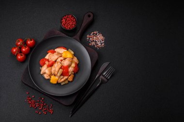 Lezzetli bir yemek tavuk dilimleri, tatlı biber ve soğan ile tuzlu ve baharatlı koyu beton arka planda.