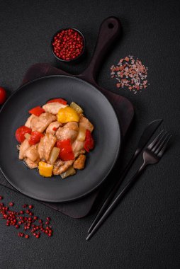 Lezzetli bir yemek tavuk dilimleri, tatlı biber ve soğan ile tuzlu ve baharatlı koyu beton arka planda.