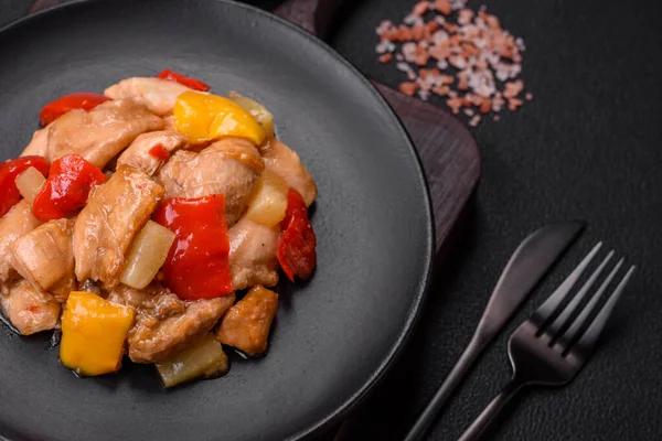 Lezzetli bir yemek tavuk dilimleri, tatlı biber ve soğan ile tuzlu ve baharatlı koyu beton arka planda.