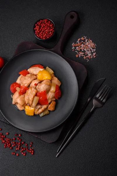 Lezzetli bir yemek tavuk dilimleri, tatlı biber ve soğan ile tuzlu ve baharatlı koyu beton arka planda.