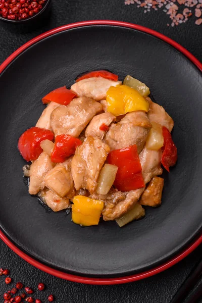 Lezzetli bir yemek tavuk dilimleri, tatlı biber ve soğan ile tuzlu ve baharatlı koyu beton arka planda.