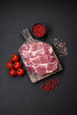 Koyu beton zeminde tuzlu, baharatlı ve otlu taze domuz bifteği.