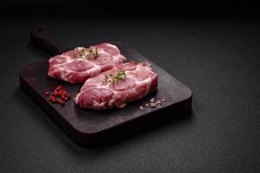Koyu beton zeminde tuzlu, baharatlı ve otlu taze domuz bifteği.