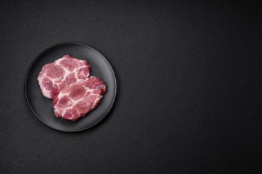 Koyu beton zeminde tuzlu, baharatlı ve otlu taze domuz bifteği.