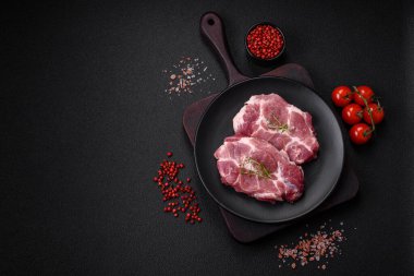 Koyu beton zeminde tuzlu, baharatlı ve otlu taze domuz bifteği.