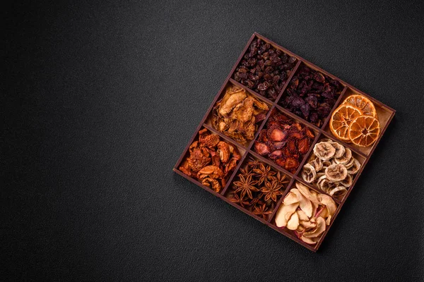 Variation of dry fruits strawberry, apple, cherry, banana, peach, plum and star anise in a box on a dark concrete background