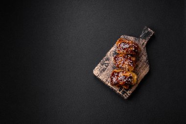 Tatlı ve ekşi teriyaki soslu lezzetli kızarmış tavuk ve koyu beton arka planda susam tohumu.