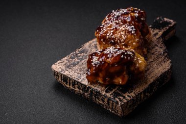 Tatlı ve ekşi teriyaki soslu lezzetli kızarmış tavuk ve koyu beton arka planda susam tohumu.