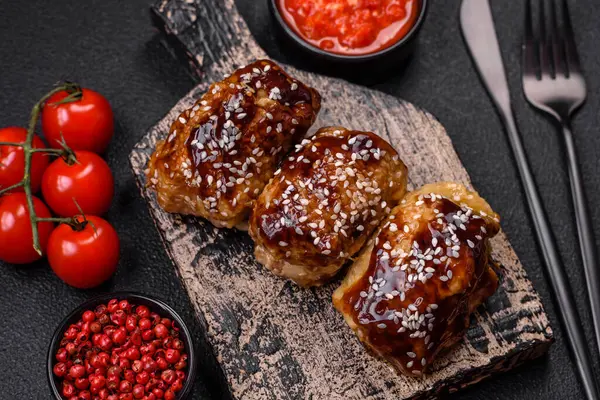 Tatlı ve ekşi teriyaki soslu lezzetli kızarmış tavuk ve koyu beton arka planda susam tohumu.