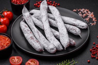 Lezzetli İspanyol füme sosis füeti. Koyu beton arka planda tuz ve baharatlarla birlikte.