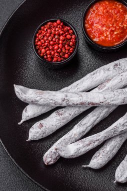 Lezzetli İspanyol füme sosis füeti. Koyu beton arka planda tuz ve baharatlarla birlikte.