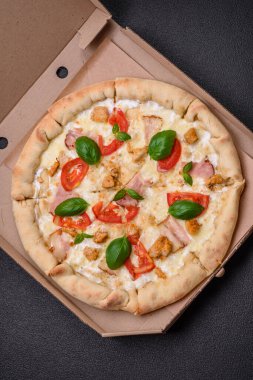 Tavuklu, domatesli, peynirli, pastırmalı, tuzlu, baharatlı ve koyu beton arkaplanlı lezzetli bir pizza.