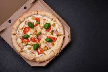 Tavuklu, domatesli, peynirli, pastırmalı, tuzlu, baharatlı ve koyu beton arkaplanlı lezzetli bir pizza.