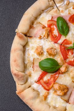 Tavuklu, domatesli, peynirli, pastırmalı, tuzlu, baharatlı ve koyu beton arkaplanlı lezzetli bir pizza.