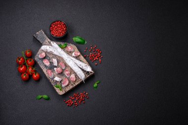 Lezzetli İspanyol füme sosis füeti. Koyu beton arka planda tuz ve baharatlarla birlikte.