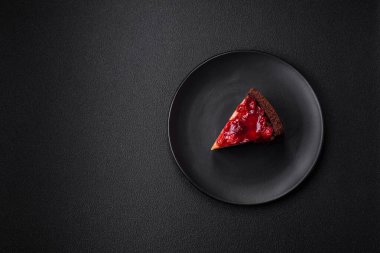 Lezzetli, peynirli, kiraz meyveli ve koyu betondan arkaplanda reçelli cheesecake keki.