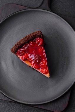 Lezzetli, peynirli, kiraz meyveli ve koyu betondan arkaplanda reçelli cheesecake keki.