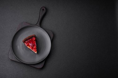 Lezzetli, peynirli, kiraz meyveli ve koyu betondan arkaplanda reçelli cheesecake keki.