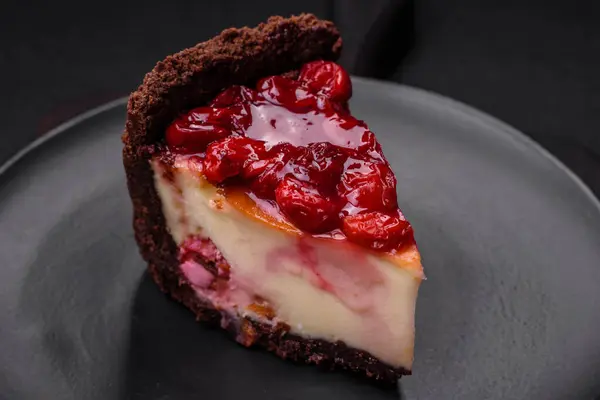 Delicious sweet cheesecake cake with mascarpone cheese, cherry berries and jam on a dark concrete background