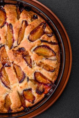 Lezzetli ev yapımı aromalı turta. Koyu beton arka planda olgun erikli.