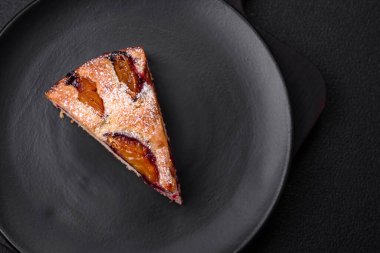 Lezzetli ev yapımı aromalı turta. Koyu beton arka planda olgun erikli.