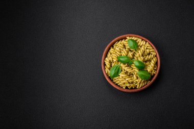 Koyu beton arka planda fesleğen, tuz ve baharatlı yeşil pesto soslu lezzetli taze makarna.