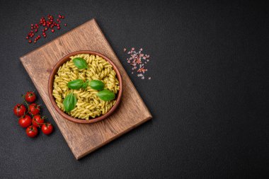 Koyu beton arka planda fesleğen, tuz ve baharatlı yeşil pesto soslu lezzetli taze makarna.