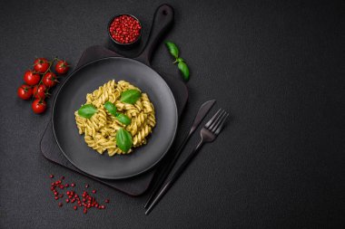 Koyu beton arka planda fesleğen, tuz ve baharatlı yeşil pesto soslu lezzetli taze makarna.