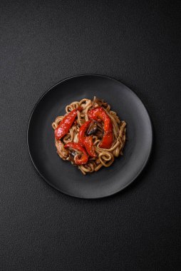 Sebzeli, mantarlı, tuzlu ve baharatlı lezzetli Asya udonu tabağı koyu beton arka planda.