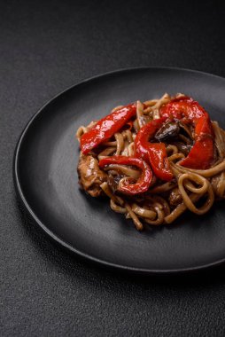 Sebzeli, mantarlı, tuzlu ve baharatlı lezzetli Asya udonu tabağı koyu beton arka planda.